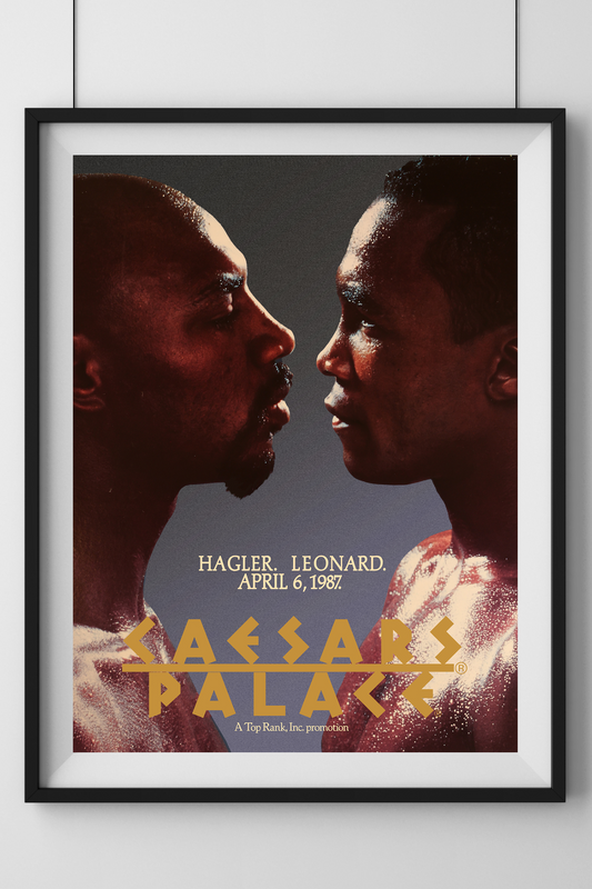 Framed poster of two boxers facing each other with text on a white wall.