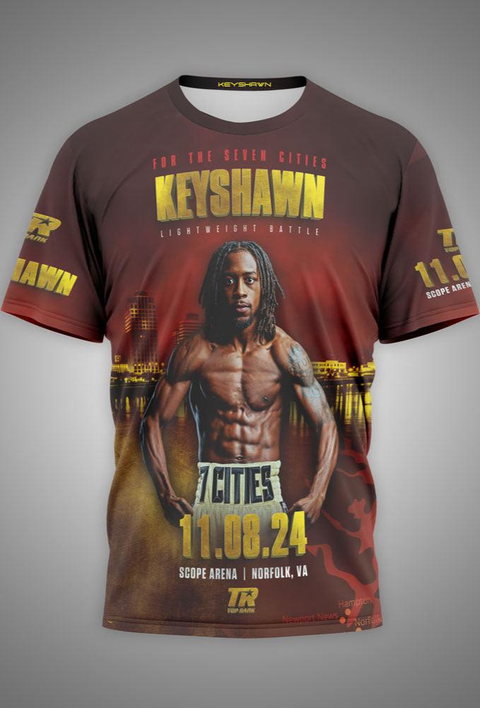 A custom-designed t-shirt featuring Keyshawn Davis in a boxing stance, displayed against a background of the Norfolk city skyline. The shirt has vibrant red, brown, and yellow tones with bold gold text that reads "Keyshawn" and "For the Seven Cities" above the image. The date "11.08.24" and "Scope Arena, Norfolk, VA" are printed below. The shirt also includes "Keyshawn" and "7 Cities" branding on the sleeves, making it a bold, eye-catching tribute to Davis' main event.